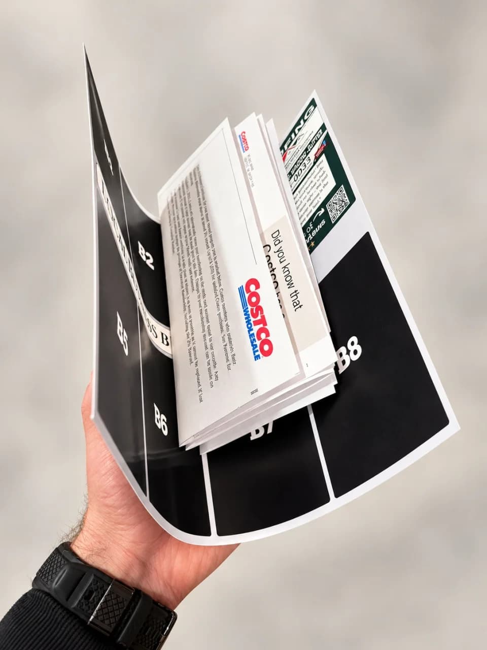The oversized card folded back over a stack of regular-size mail, showing how much larger it is.